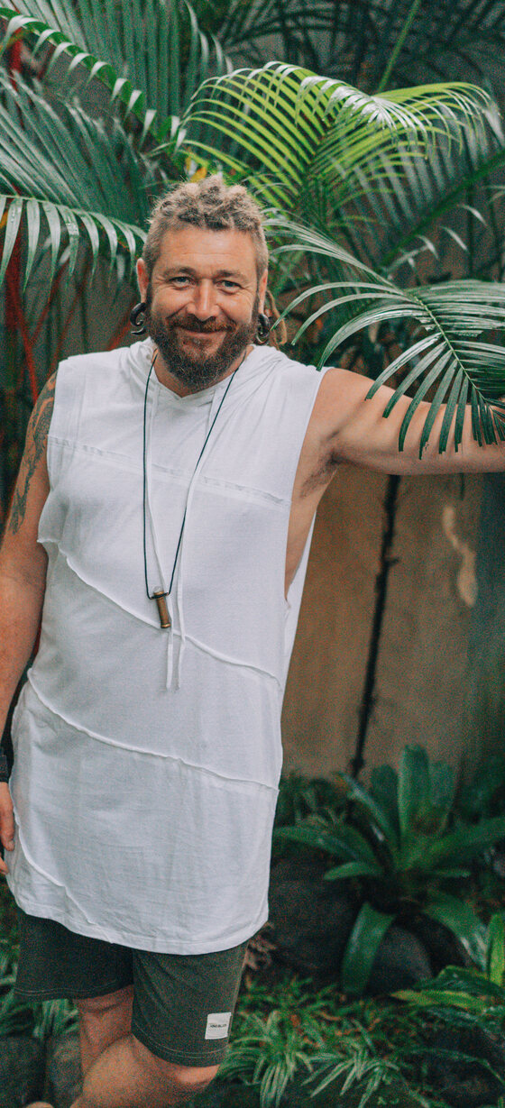 Chenzo, certified Dutch teacher, smiling outdoors among palm leaves